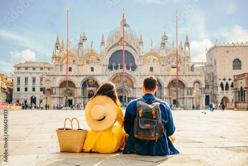 couple sitting on the ground enjoying the view of saint marco square Venice Italy