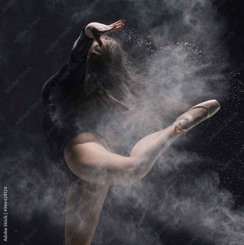 Woman in black body jump with dust cloud profile shot