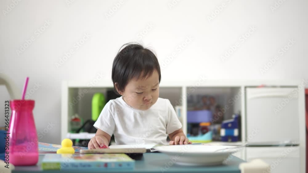 Asian Chinese toddler at home in apartment flipping books Asian Chinese toddler at home in apartment flipping books