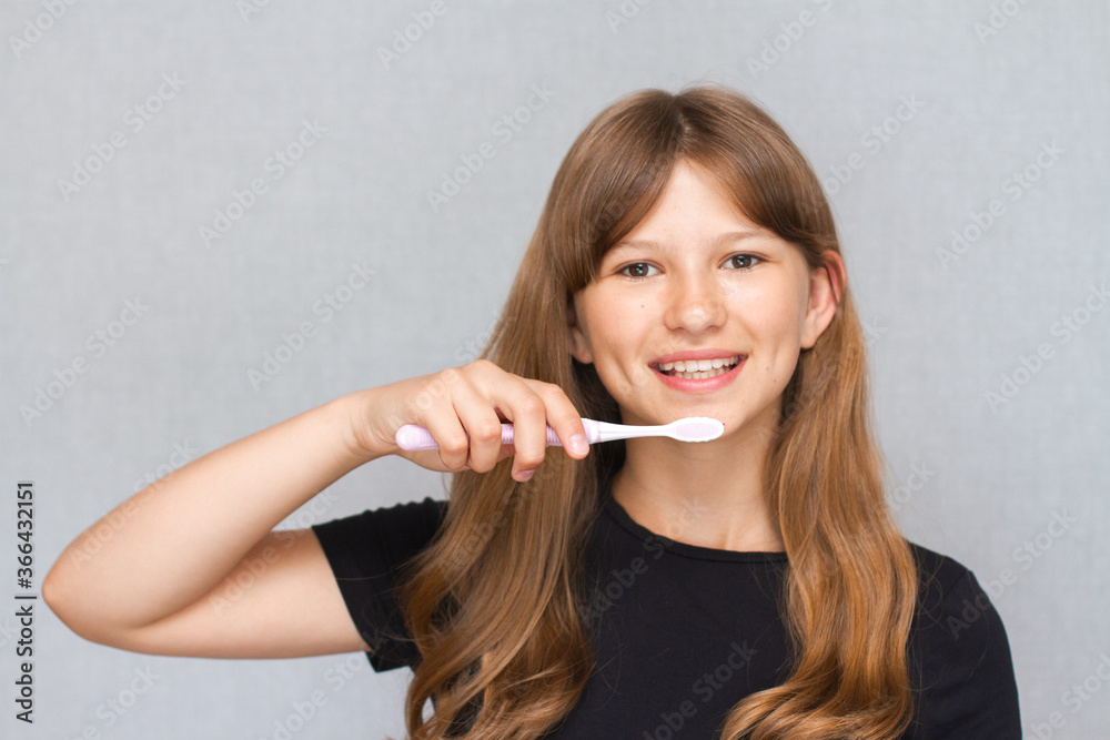 Beautiful young cute little girl brushing her teeth. Dental hygiene. Morning routine. Gray background Beautiful young cute little girl brushing her teeth. Dental hygiene. Morning routine. Gray background