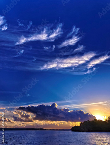 Wispy white Cirrus and dark Cumulonimbus clouds in a seascape sunrise Sunrise. Kaurie Creek  The Sandy Straits  Queensland  Australia.