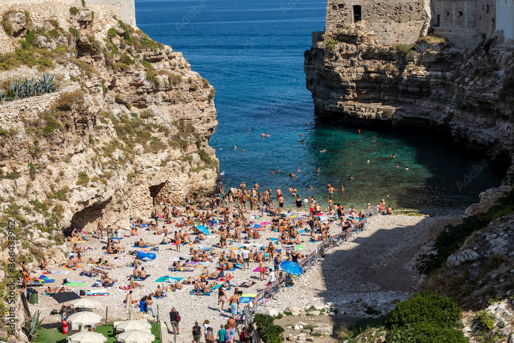 People relax and swimming on lovely beach Lama Monachile in Polignano a Mare, Adriatic Sea, Apulia, Bari province, Italy,