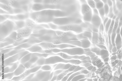 Closeup of desaturated transparent clear calm water surface texture with splashes and bubbles. Trendy abstract nature background. White-grey water waves in sunlight