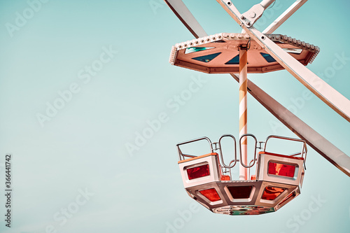Single Ferris wheel car with cloudless sky in background, color toning applied, space for text.