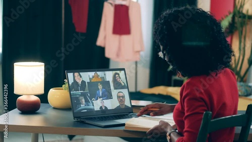 Online studing concept. African lady is using a laptop and a book in her online lesson photo