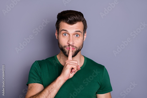 Photo of attractive handsome guy holding finger on lips boss have important meeting ask keep silence colleagues wear casual green t-shirt isolated grey color background