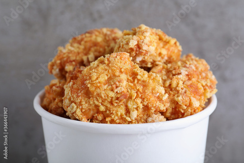 Bucket with yummy nuggets on blurred grey background, closeup