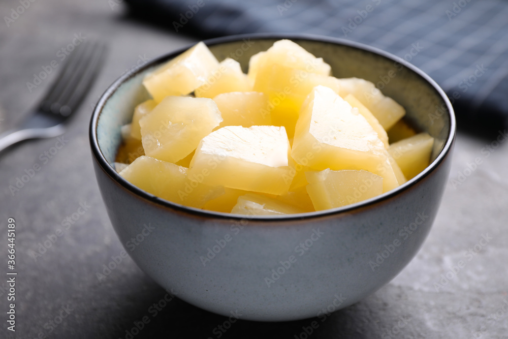 Tasty canned pineapple in bowl on grey table, closeup Tasty canned pineapple in bowl on grey table, closeup
