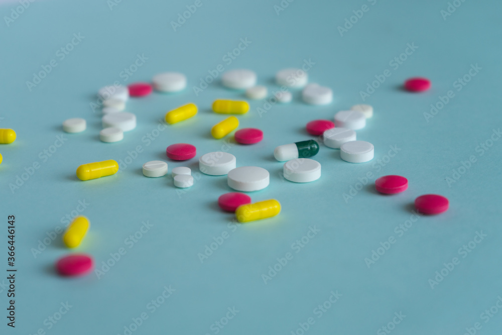 Tablets of different shapes and colors are scattered randomly. White, yellow, pink. Medical concept on blue background, pharmacy theme. Tablets of different shapes and colors are scattered randomly. White, yellow, pink. Medical concept on blue background, pharmacy theme.