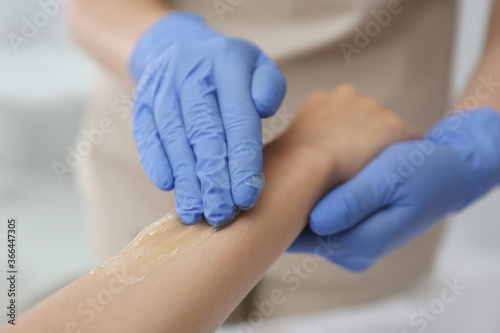 Woman getting wax epilation of arm in salon, closeup