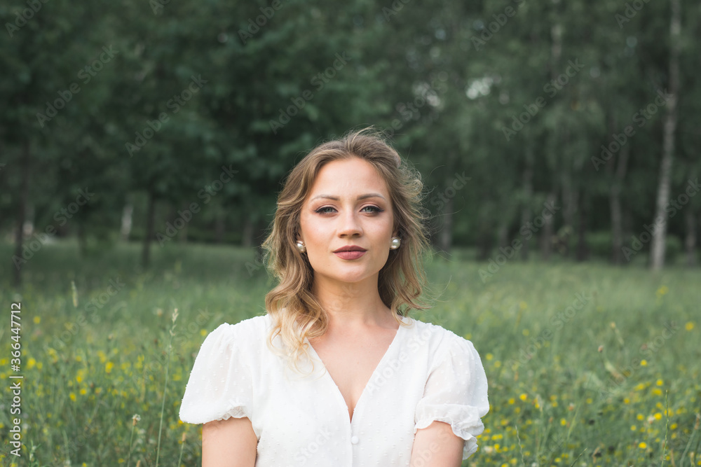 Portrait of a beautiful Russian girl sitting in a beautiful white dress on the lawn Portrait of a beautiful Russian girl sitting in a beautiful white dress on the lawn