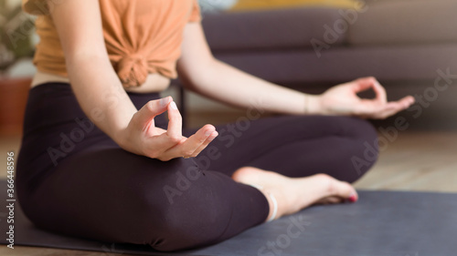 Young sporty woman doing yoga meditation at home on the floor