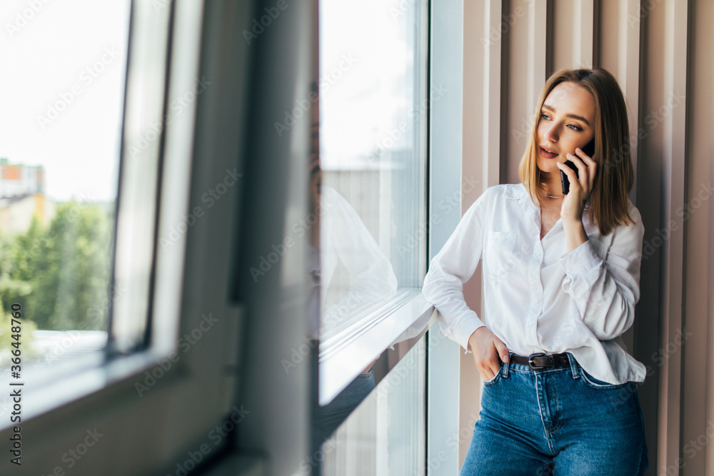 Beautiful young business woman sitting at office desk and talking on phone Beautiful young business woman sitting at office desk and talking on phone