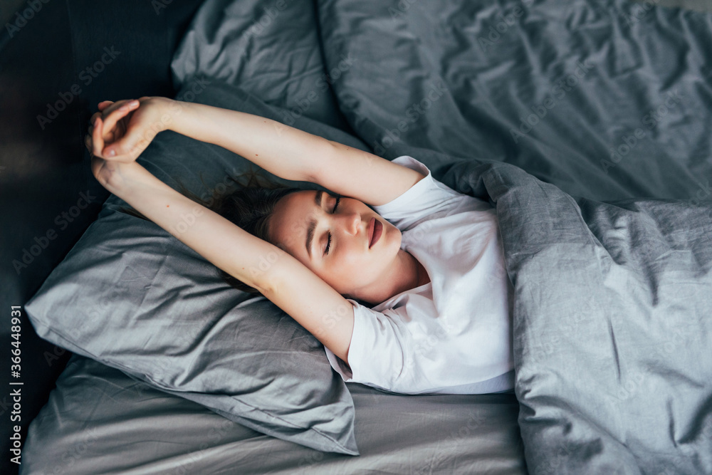 attractive woman stretching in the morning and is smiling in her bed