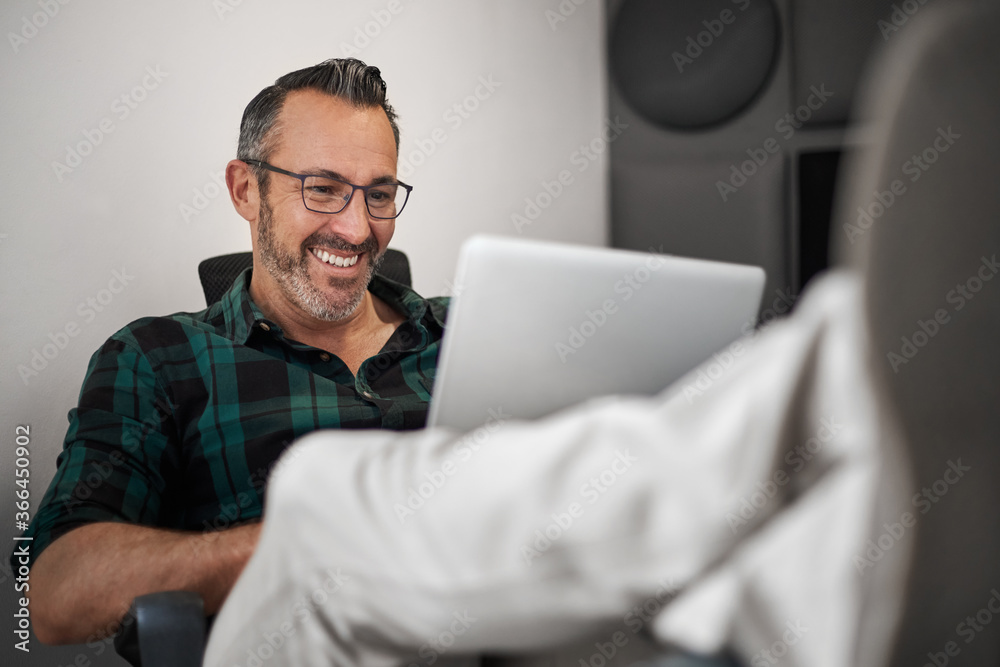 Smiling businessman working with his feet up on his desk Smiling businessman working with his feet up on his desk