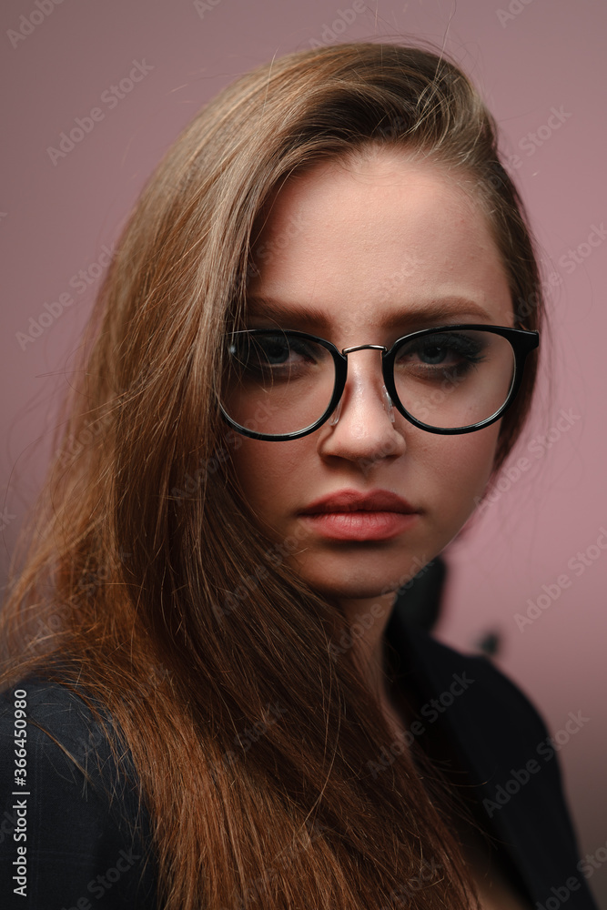 A young girl 20-25 years old in glasses, a jacket in the image of a teacher posing on a pink background. A young girl 20-25 years old in glasses, a jacket in the image of a teacher posing on a pink background.