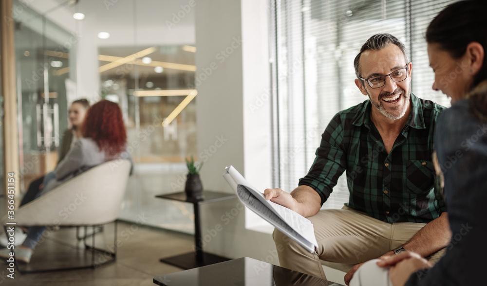Smiling mature businessman going over paperwork with an office coworker Smiling mature businessman going over paperwork with an office coworker