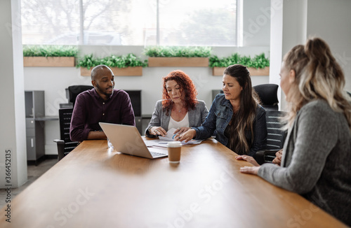 Diverse team of businesspeople meeting together around an office