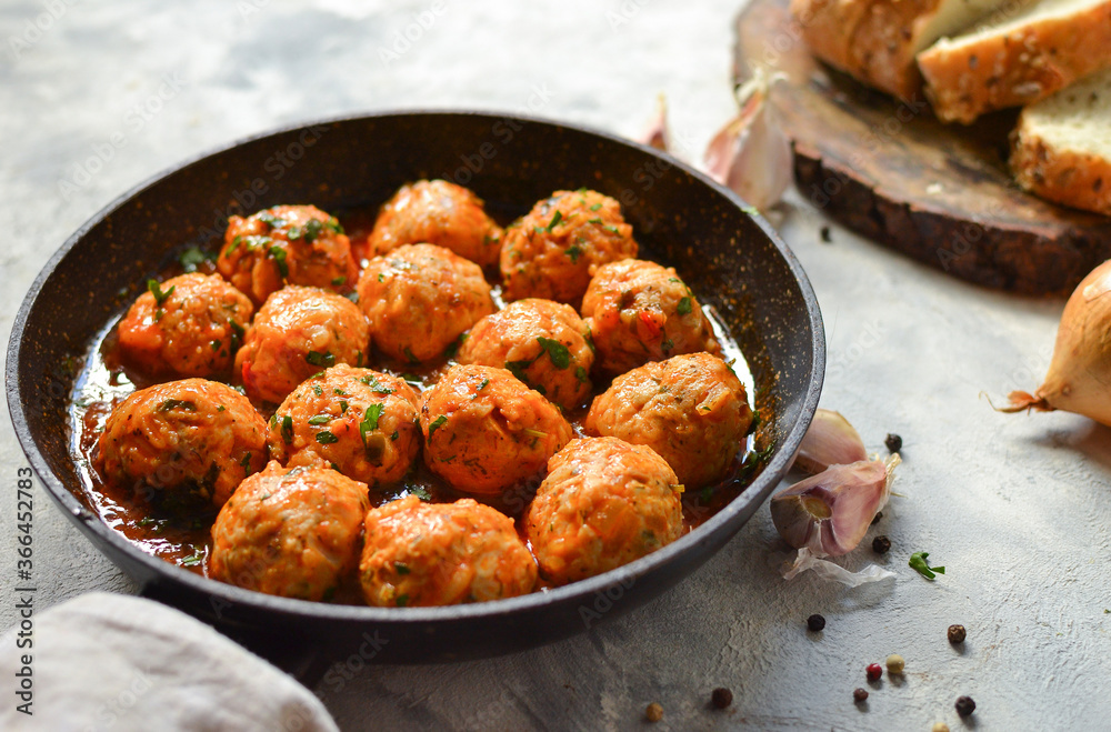 Chicken meatballs in tomato sauce in a pan. Recipe and Step by Step Cooking. Light decorative background.