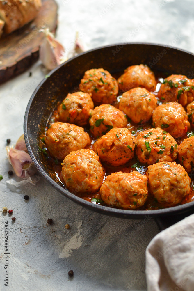 Chicken meatballs in tomato sauce in a pan. Recipe and Step by Step Cooking. Light decorative background. Vertical view