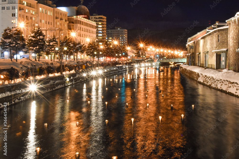 Paisaje nocturno, invernal, se observa un canal con iluminaciones