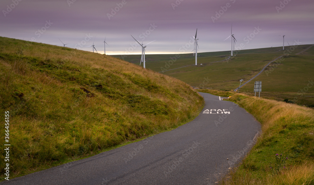 Wind turbines and a winding road on the Betws mountain in South Wales, UK