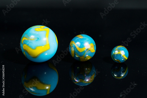 Blue and Yellow Colorful Marble Balls on Black background with reflection. Abstract Pattern