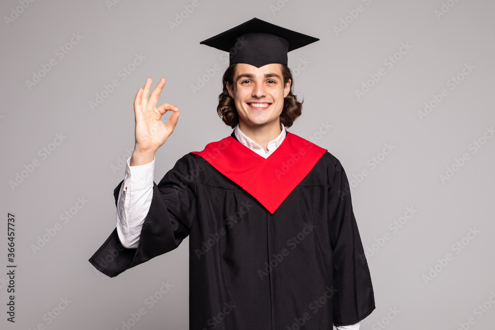 Young handsome graduate man with long hair holding degree over isolated background doing ok sign with fingers, excellent symbol Young handsome graduate man with long hair holding degree over isolated background doing ok sign with fingers, excellent symbol