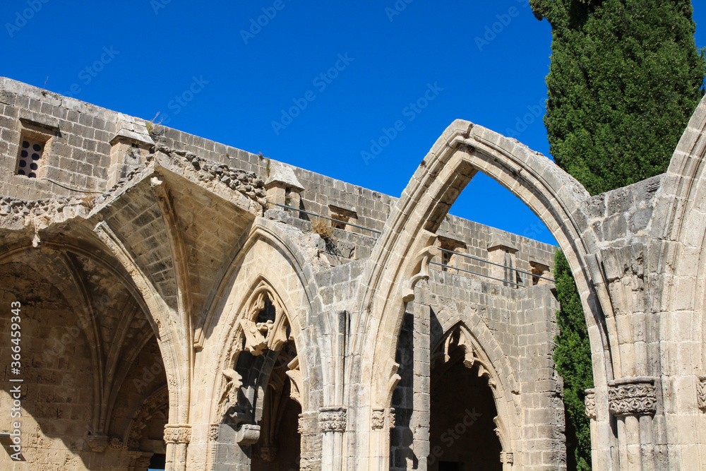Fragment of Bellapais Abbey, White Abbey, Abbey of the Beautiful world. Arches and cypress against the blue sky.