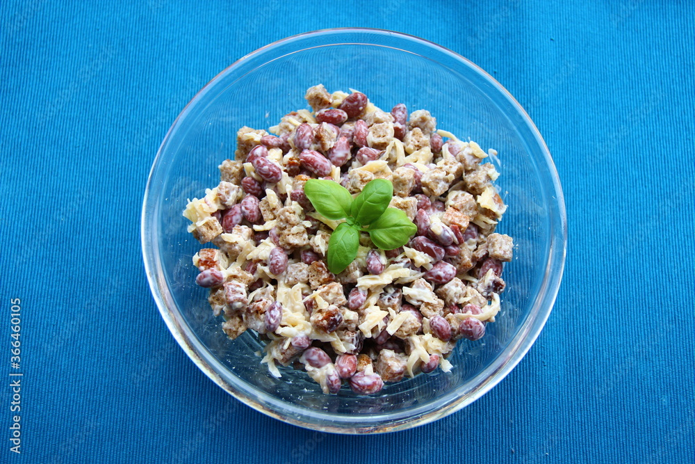 Salad with canned beans, cheese and scallops in a transparent bowl on a blue background Salad with canned beans, cheese and scallops in a transparent bowl on a blue background