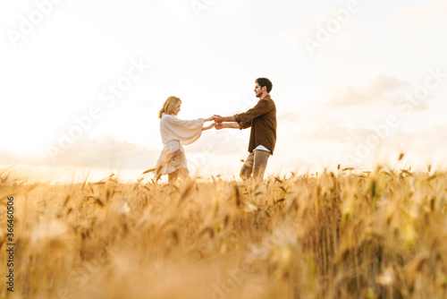 Image of young caucasian couple dancing in golden field on countryside