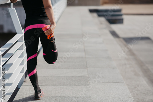 Sport lifestyle and outdoor workouts. African american girl doing exercises to prepare for running