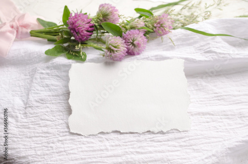 Wedding mockup with pink flowers and delicate silk ribbons on a white background. Greeting card or wedding invitation with jagged edges. Flat lay, top