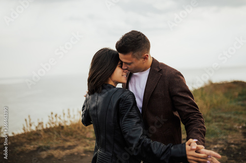 Passionate romantic couple hugging on the nature. Tender couple hugs. Young couple are happy and standing on a meadow in the morning on autumn season. Green grass on background.