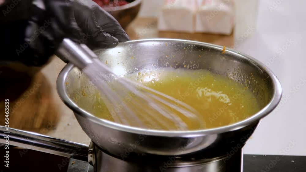 Close up of chef stirring the butter and egg yolks, holding the bowl over a pan of boiling water for heating the mixture. 4K Close up of chef stirring the butter and egg yolks, holding the bowl over a pan of boiling water for heating the mixture. 4K