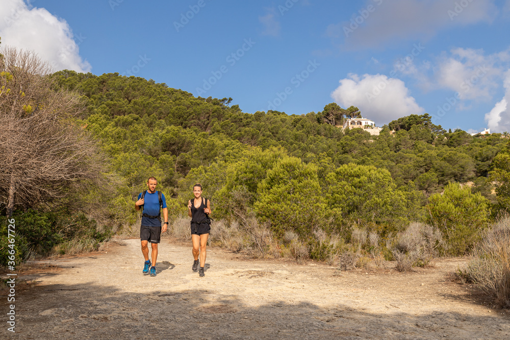 Couple of smiling trekkers walking along a footpath. Sunny day blue sky Couple of smiling trekkers walking along a footpath. Sunny day blue sky