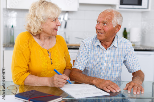 Portrait of mature couple in home interior filling up documents