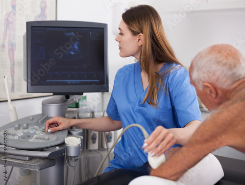 Female doctor using ultrasound scan examining male patient at modern hospital