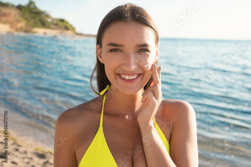 Girl Applying Sun Cream On Face For UV-Protection At Seaside © Prostock-studio