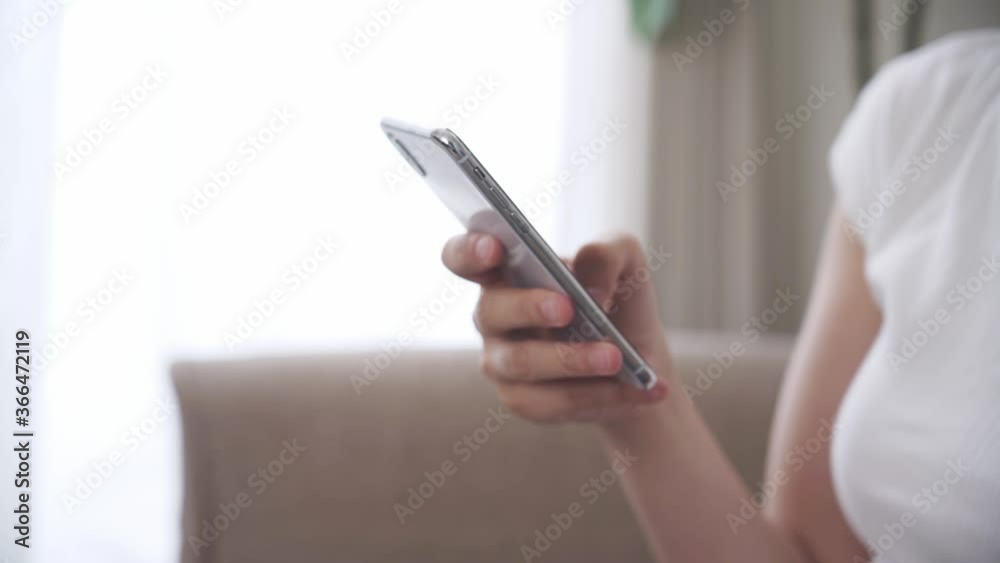 家でスマートフォンを操作する女性