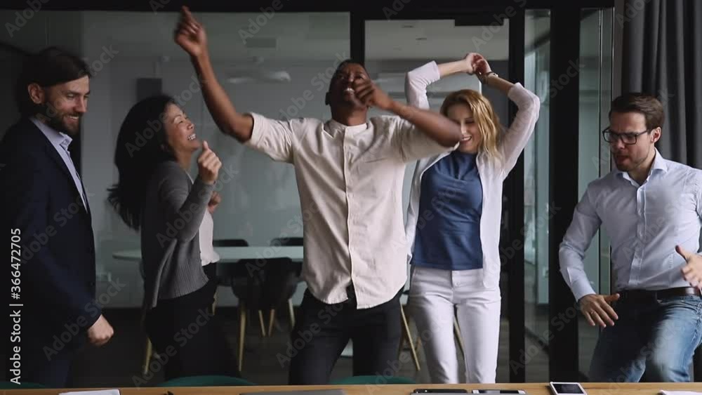Motivated funny diverse business team people dancing celebrating success at corporate party on friday, happy friendly multiracial coworkers group having fun together enjoy victory dance in office
