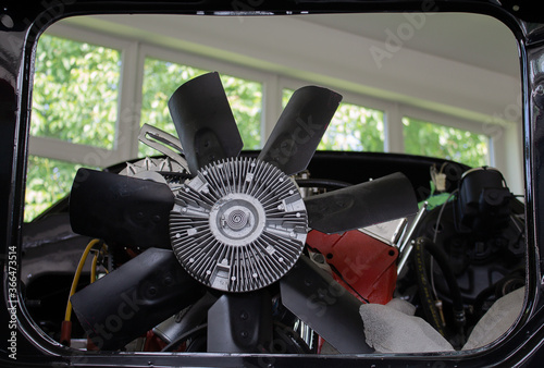 Fan wheel of a V8 engine built into a body shell of a muscle car. Taken close up.