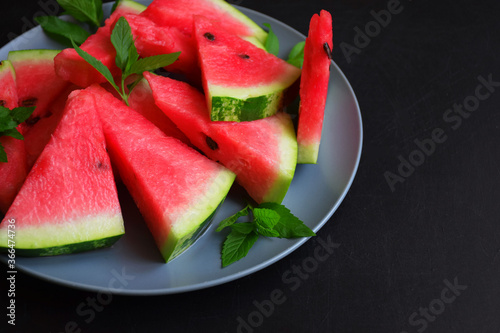 Ripe juicy watermelon on a plate on a dark background