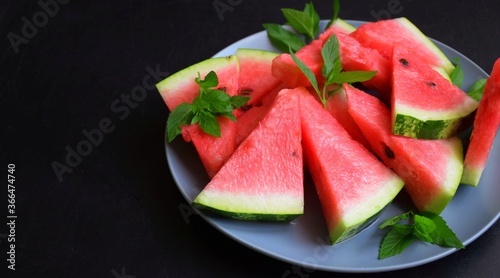 Ripe juicy watermelon on a plate on a dark background