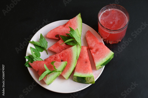 Refreshing watermelon smoothie and bowl of watermelon on dark background