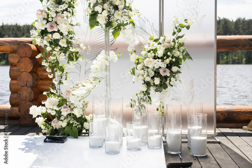Close up of wedding ceremony with white transparent screens and fresh white flowers and candles