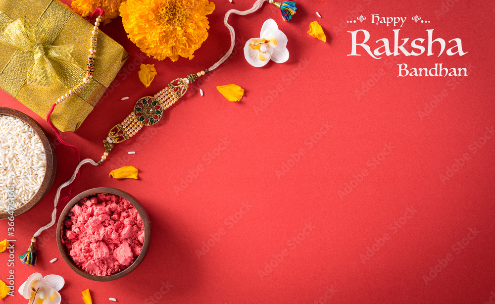 Raksha Bandhan, Indian festival with beautiful Rakhi and  Rice Grains on red background.  A traditional Indian wrist band which is a symbol of love between Sisters and Brothers. - obrazy, fototapety, plakaty 