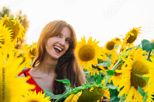 Happy woman with sunflwer enjoying nature and laughing on summer sunflower field. photo