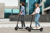 Couple riding motorized kick scooters in the city