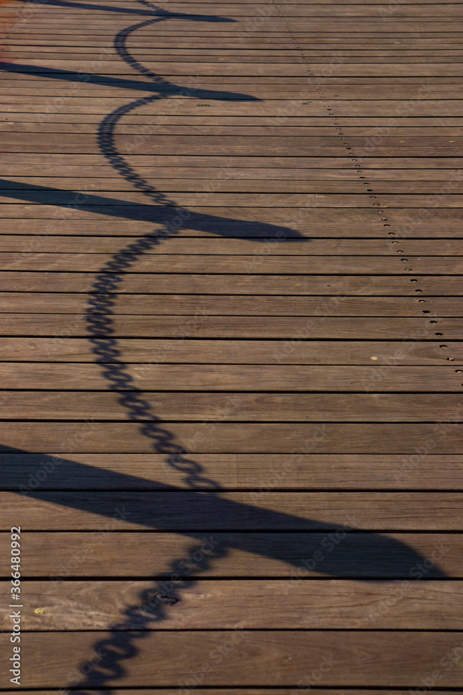 Shadow of chain fence on the old wood bridge. Shadow of chain fence on the old wood bridge.